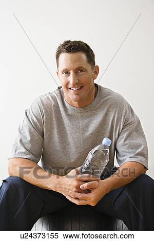 Man holding water bottle sitting on balance ball at gym smiling. View Large Photo Image Stock Photography - Man holding water bottle sitting on balance ball at gym smiling.. Fotosearch