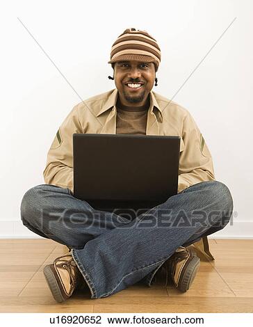 Man sitting on floor with a laptop computer View Large Photo Image Stock Image - Man sitting on floor with a laptop computer. Fotosearch