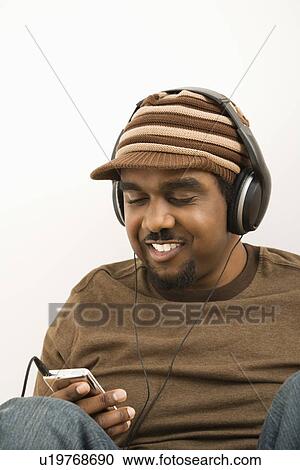 Stock Image - Man wearing hat and listening to mp3 player. Fotosearch