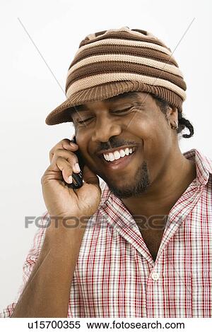Stock Photography - Man wearing hat and smiling while talking on cell phone. Fotosearch