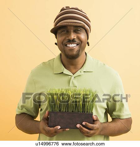 Man wearing hat holding potted grass View Large Photo Image Stock Photograph - Man wearing hat holding potted grass . Fotosearch