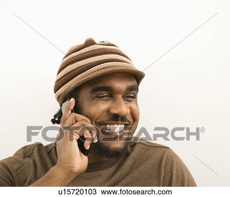 Stock Image - Man wearing hat talking on cell phone. Fotosearch