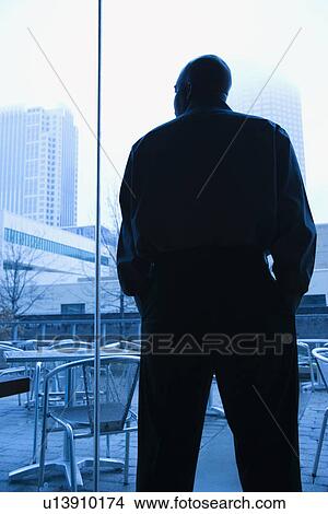 Mid-adult African American male looking out window. View Large Photo Image Picture - Mid-adult African American male looking out window. . Fotosearch