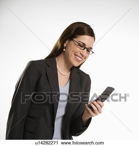 Stock Image - Mid adult professional business woman text messaging on cell phone. Fotosearch