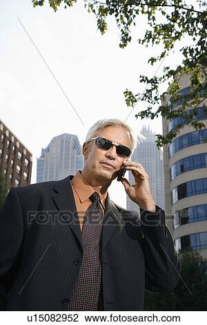 Middle aged businessman in sunglasses talking outdoors on cell phone View Large Photo Image Stock Image - Middle aged businessman in sunglasses talking outdoors on cell phone. Fotosearch
