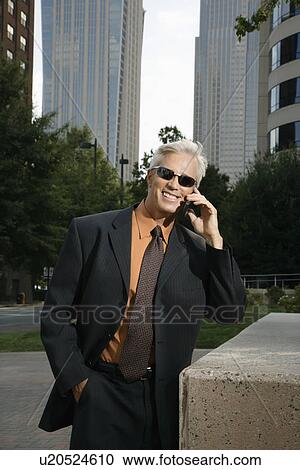 Middle aged businessman in sunglasses talking outdoors on cell phone View Large Photo Image Stock Image - Middle aged businessman in sunglasses talking outdoors on cell phone. Fotosearch