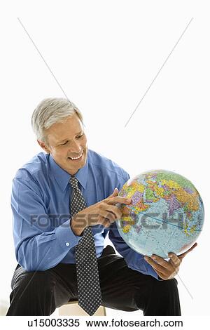 Stock Photography - Middle aged Caucasian man holding globe and pointing.. Fotosearch