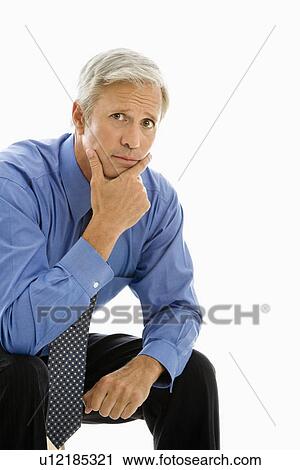 Stock Image - Middle aged Caucasian man looking at viewer with hand to chin.. Fotosearch