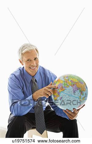 Picture - Middle aged Caucasian man pointing on globe.. Fotosearch