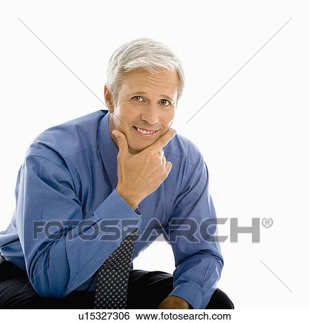 Stock Photograph - Middle aged Caucasian man smiling at viewer with hand to chin.. Fotosearch