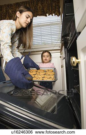 Mother and daughter taking cookies out of oven View Large Photo Image Stock Photograph - Mother and daughter taking cookies out of oven. Fotosearch