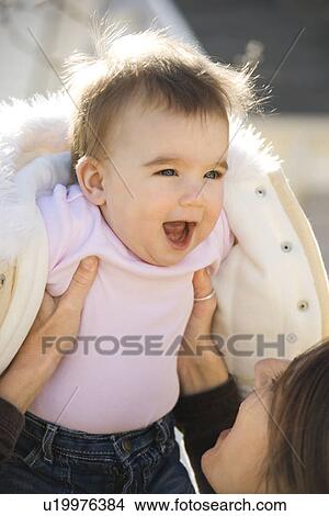 Picture - Mother holding up smiling baby girl. Fotosearch