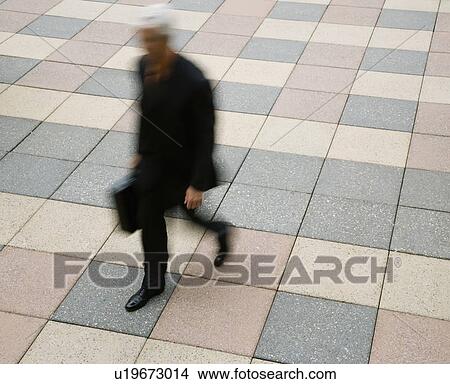 Motion blur of Caucasian businessman walking outdoors with briefcase. View Large Photo Image Picture - Motion blur of Caucasian businessman walking outdoors with briefcase.. Fotosearch