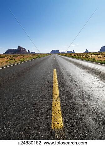 Stock Image - Open highway in scenic desert landscape with distant mountains and mesas.. Fotosearch