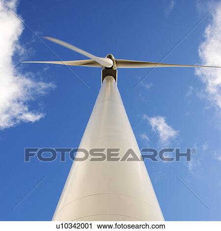 Stock Image - Perspective shot of wind turbine against blue sky.. Fotosearch