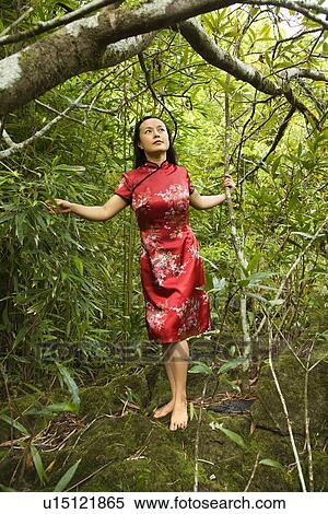 Stock Photography - Portrait of Asian American woman in ethnic attire standing on rock in bamboo in Maui, Hawaii.. Fotosearch