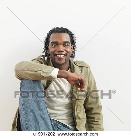 Portrait of man sitting against white background smiling. View Large Photo Image Stock Image - Portrait of man sitting against white background smiling.. Fotosearch