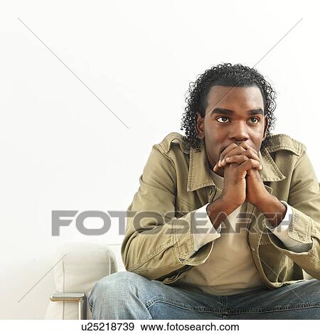 Stock Photo - Portrait of man sitting with hands clasped as if in thought.. Fotosearch