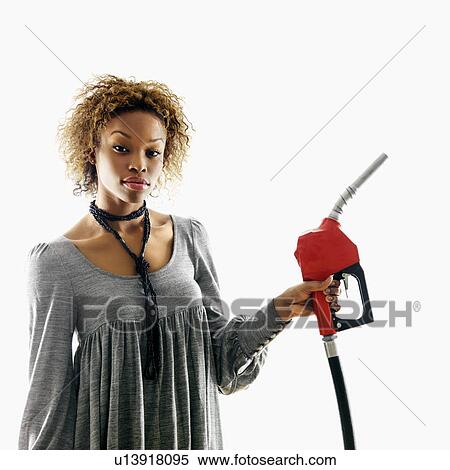 Stock Photography - Portrait of pretty young woman holding gas pump nozzle on white background. Fotosearch
