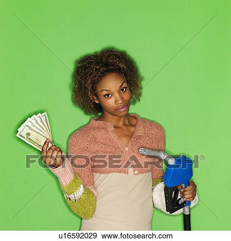 Portrait of pretty young woman standing against green background holding gasoline pump nozzle and money. View Large Photo Image Stock Photo - Portrait of pretty young woman standing against green background holding gasoline pump nozzle and money.. Fotosearch