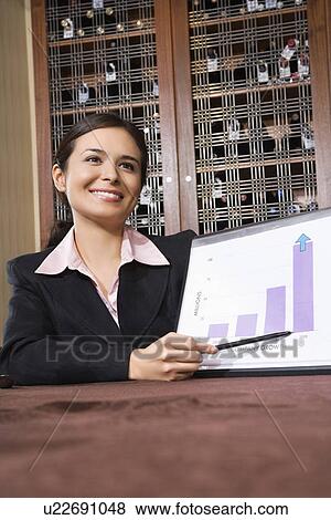 Stock Photo - Pretty businesswoman smiling and pointing to bar graph. Fotosearch