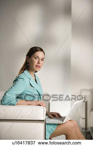 Stock Photo - Professional business woman sitting in modern office working on laptop computer. Fotosearch