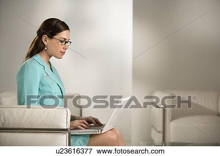 Stock Photo - Professional business woman sitting in modern office working on laptop computer. Fotosearch
