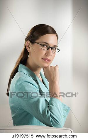 Professional business woman sitting in modern office looking at viewer slightly smiling View Large Photo Image Stock Photography - Professional business woman sitting in modern office looking at viewer slightly smiling. Fotosearch