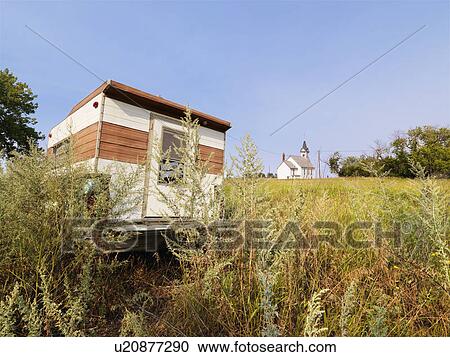 Stock Image - Recreational vehicle in overgrown field with rural church in distance. Fotosearch