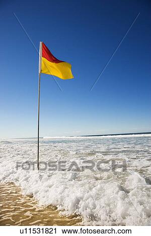 Stock Image - Red and yellow flag on beach in Surfers Paradise, Australia. Fotosearch
