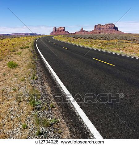 Stock Photograph - Road in scenic desert landscape with mesa and mountains.. Fotosearch