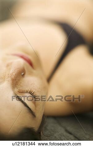 Selective focus close up of young woman lying on rock View Large Photo Image Picture - Selective focus close up of young woman lying on rock. Fotosearch