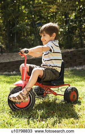 Side view of Hispanic boy riding red tricycle in grass. View Large Photo Image Stock Image - Side view of Hispanic boy riding red tricycle in grass.. Fotosearch