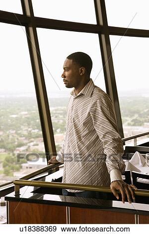 Stock Photo - Side view of mid adult man in tower restaurant looking out window at view. Fotosearch