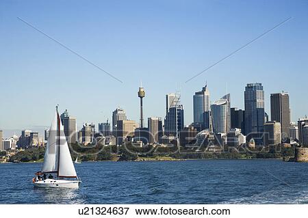 Stock Photo - Skyscrapers and sailboat on Sydney Harbour in Sydney, Australia. Fotosearch