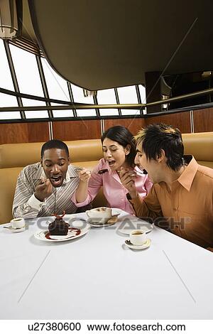 Stock Image - Small group of friends eating dessert at a restaurant. Fotosearch