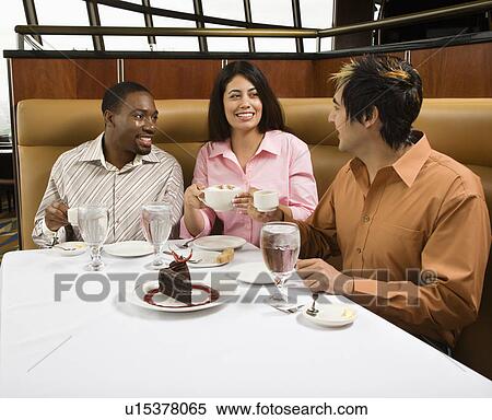 Stock Photography - Small group of mid adult friends at restaurant talking and having dessert. Fotosearch