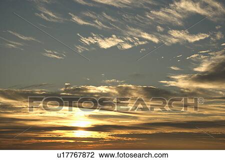 Stock Image - Sun in blue sky with clouds.. Fotosearch