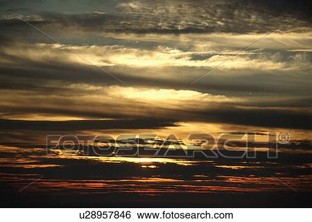 Sunset through cloudy sky View Large Photo Image Stock Photograph - Sunset through cloudy sky. Fotosearch