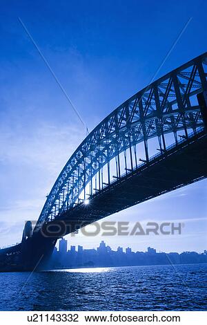 Stock Image - Sydney Harbour Bridge at dusk with view of distant skyline and harbour in Sydney, Australia.. Fotosearch