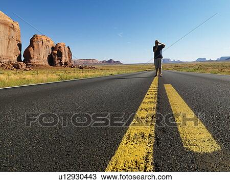 Teenage boy taking photograph standing in open road in the desert with landforms View Large Photo Image Stock Image - Teenage boy taking photograph standing in open road in the desert with landforms. Fotosearch