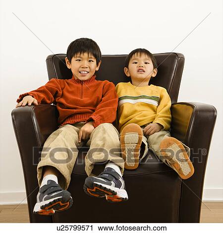 Two Asian brothers sitting in chair smiling. View Large Photo Image Stock Image - Two Asian brothers sitting in chair smiling.. Fotosearch