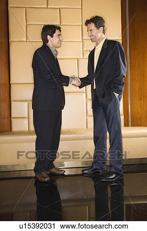 Two businessmen standing and shaking hands View Large Photo Image Stock Image - Two businessmen standing and shaking hands. Fotosearch