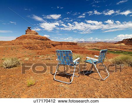 Stock Image - Two lawn chairs in scenic desert landscape with land formation.. Fotosearch