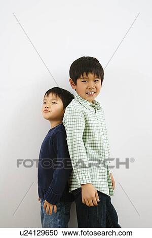 Two young Asian brothers standing back to back. View Large Photo Image Stock Image - Two young Asian brothers standing back to back.. Fotosearch