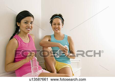 Two young women in fitness clothes holding water bottles smiling at camera View Large Photo Image Stock Image - Two young women in fitness clothes holding water bottles smiling at camera. Fotosearch