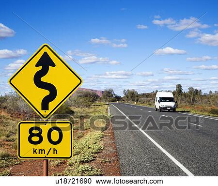 Stock Image - Van on asphalt two lane road in rural Australia with speed limit and curve ahead road sign.. Fotosearch