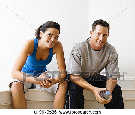 Stock Photograph - Woman and man sitting wearing active wear. Fotosearch