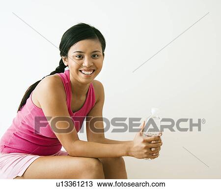 Stock Image - Woman holding bottle of water. Fotosearch