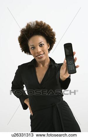 Stock Image - Woman holding cellphone out to view standing against white background.. Fotosearch